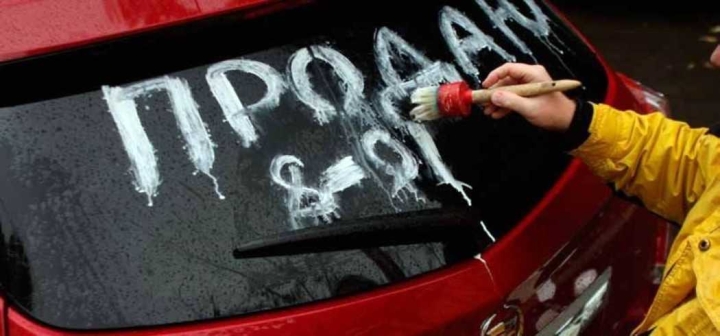 Мужчина пишет краской на стекле автомобиля